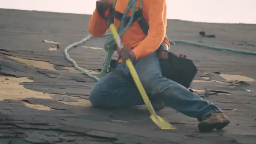 Roofer removing old shingles during a roof replacement